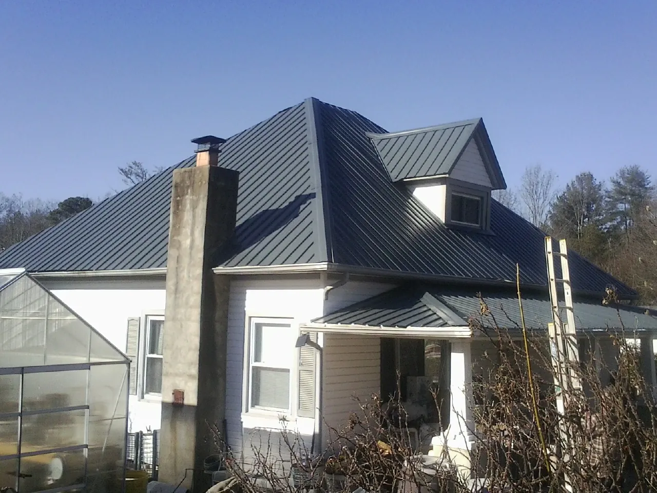 Dark blue standing seam metal roof on a white farmhouse with dormer — Slate & Tile Roof Repair by Roofing Brothers in Jim Thorpe