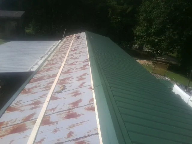 Old rusted panels beside newly installed green metal roofing — Wind Damage Roof Repair by Roofing Brothers in Jim Thorpe