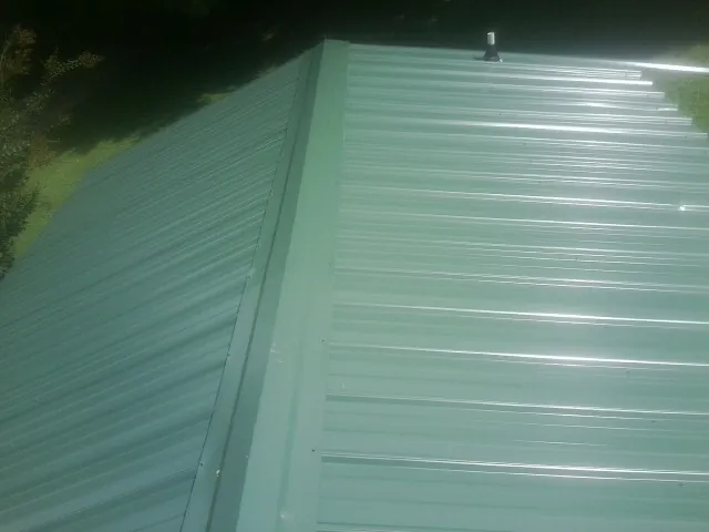 New green metal panels meeting at the ridge of a roof — Flat Roof Repair work by our crew in Jim Thorpe