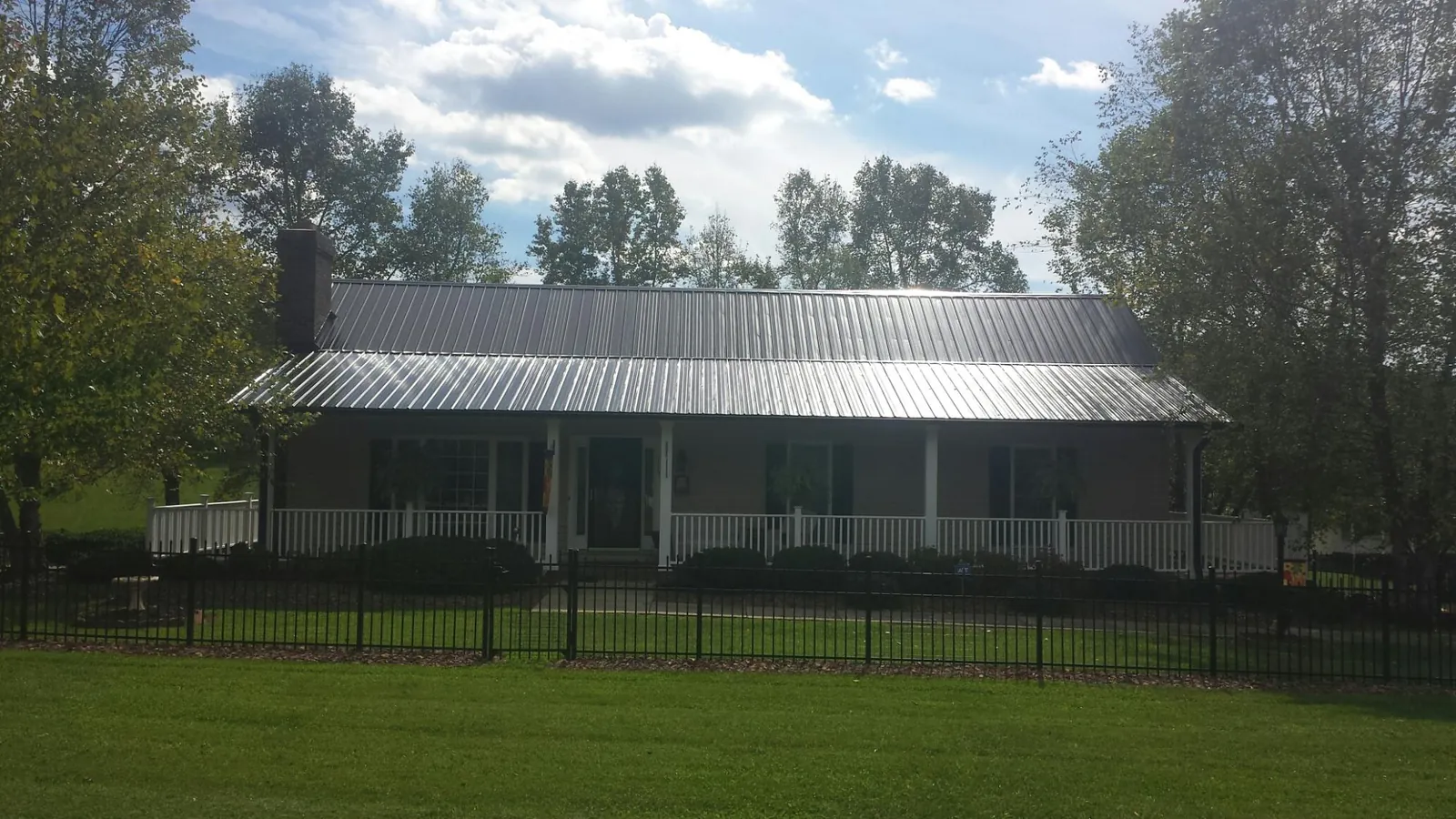 Gray metal roof on a brick ranch with a full width front porch — Gutter Guard Installation work by our crew in Jim Thorpe
