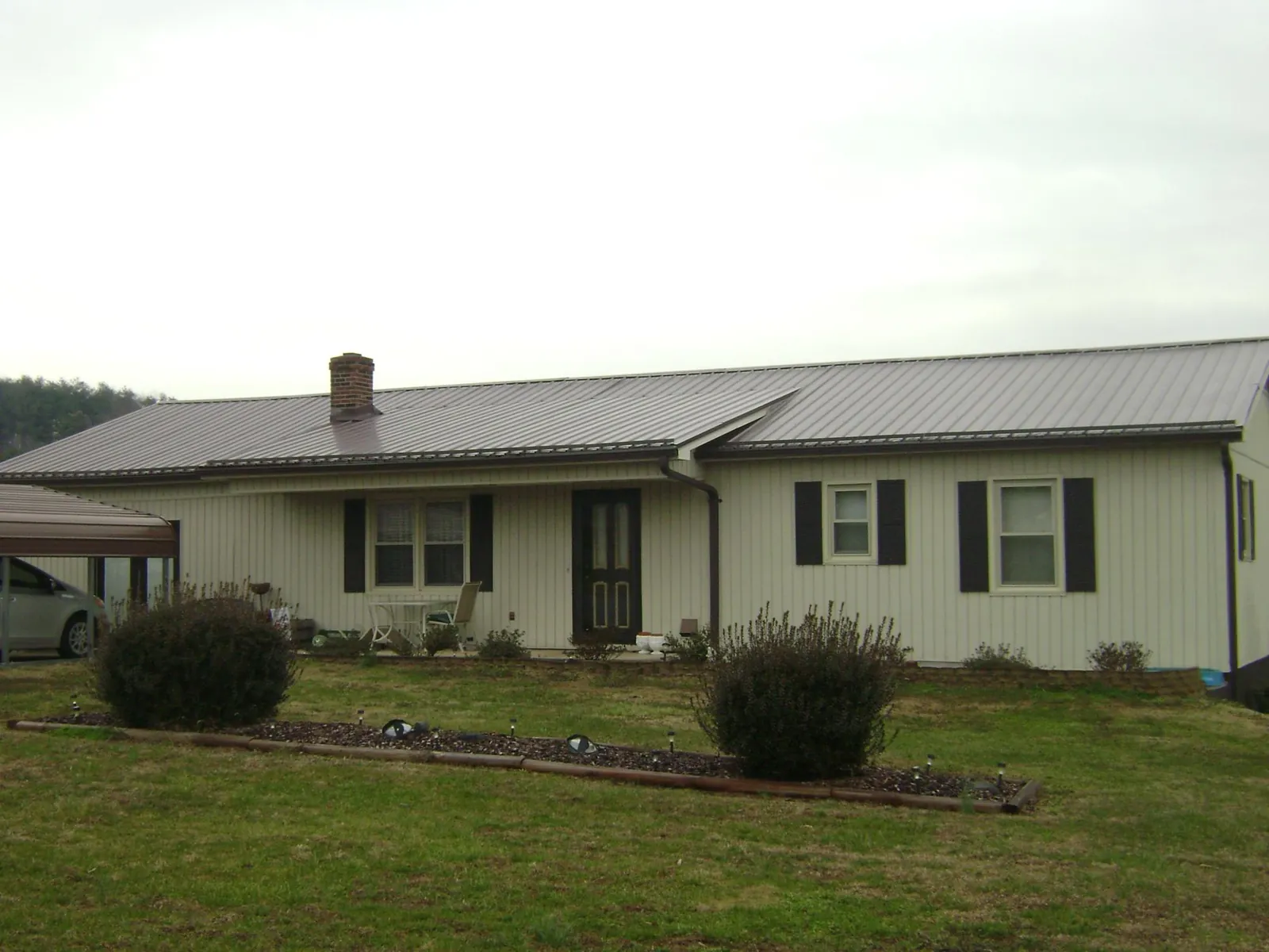 Brown metal roof on a cream sided ranch home with a brick chimney in Jim Thorpe