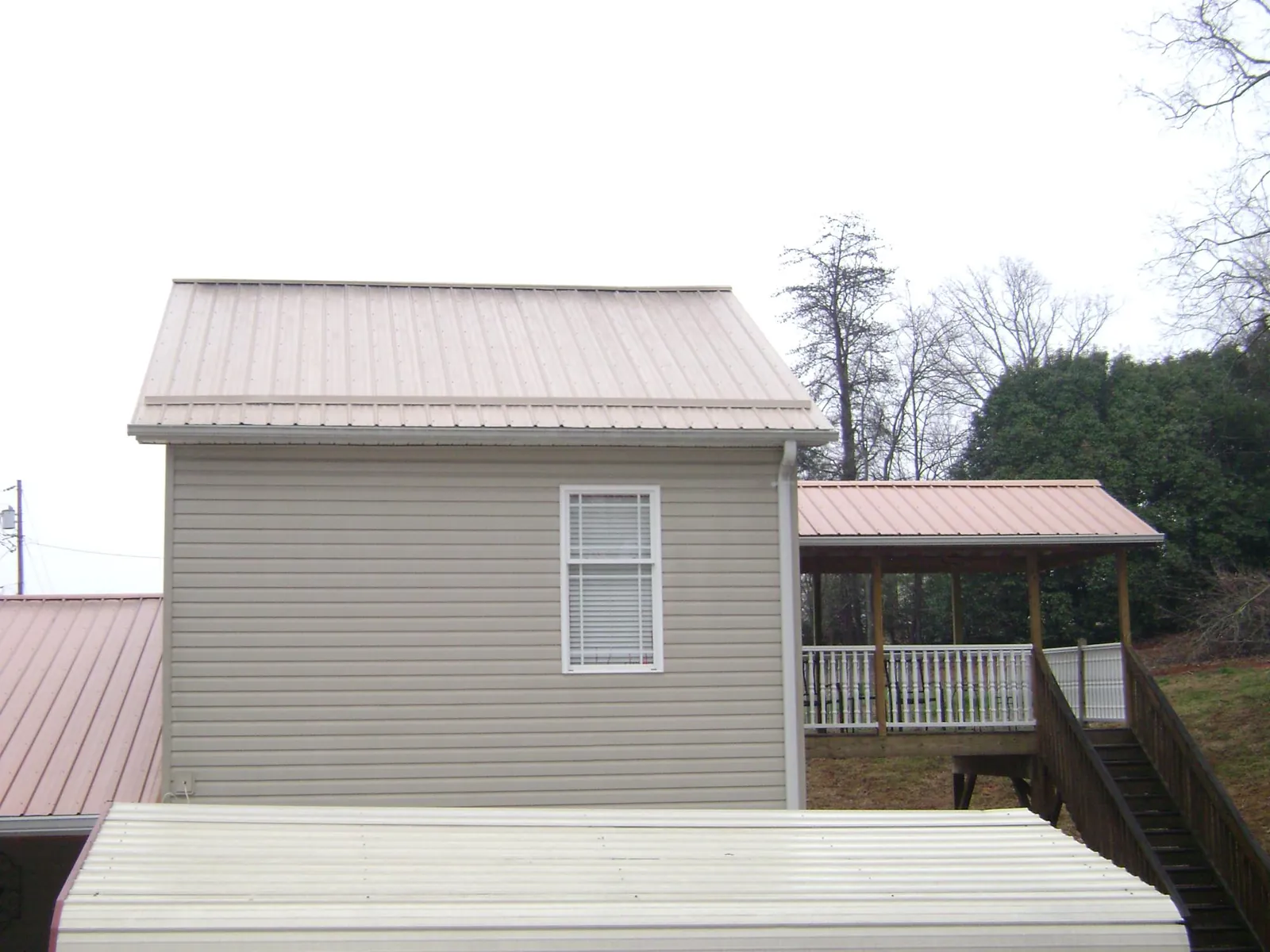 Tan metal roofs on a two story addition and attached porch, from a Roof Replacement job in Jim Thorpe