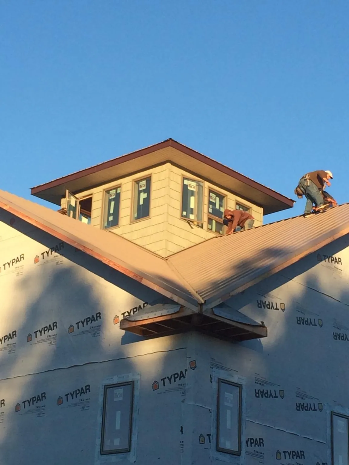 Roofers working around a rooftop cupola on a new metal roof at sunset — Roof Waterproofing in Jim Thorpe by Roofing Brothers